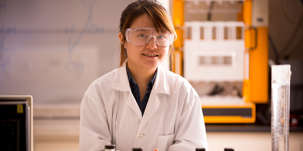 Student in the lab wearing lab coat and goggles